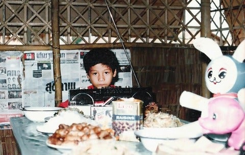 Child at a dinner table in a hut.