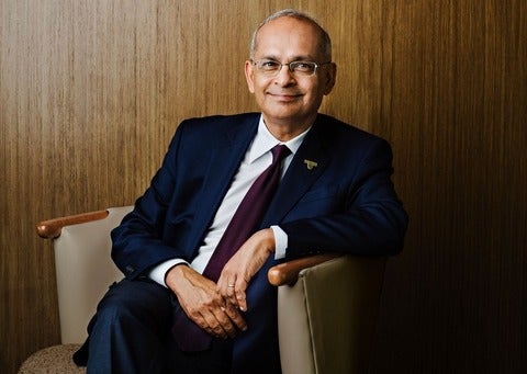 Vivek Goel wearing a suit and sitting on a beige chair
