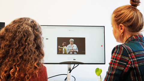 Two women watching the play on a screen