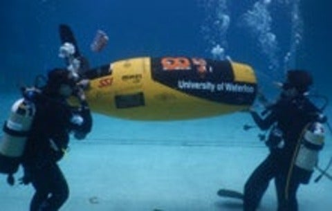 Members of the WatSub team race their submarine, AMY