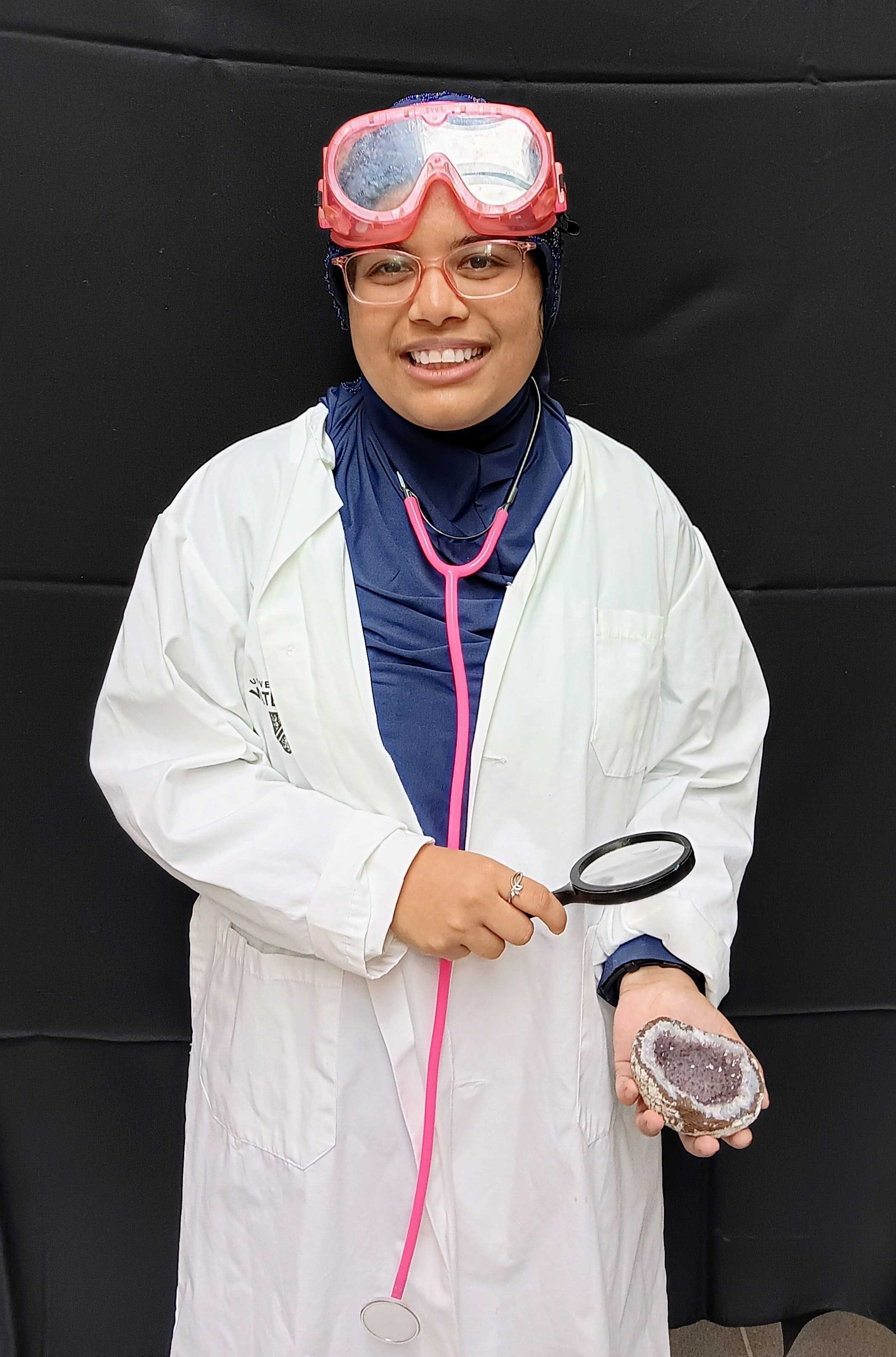 Tasbiha Saif Ansari wears a lab coat and safety equipment while examining a geod