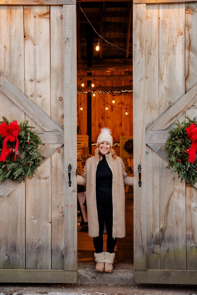Rebecca Hope stands in a doorway decorated with wreaths