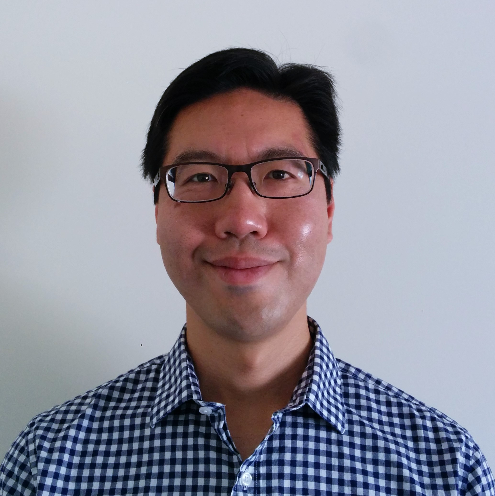 Thomas Looi wearing a plaid blue and white shirt with dark framed glasses