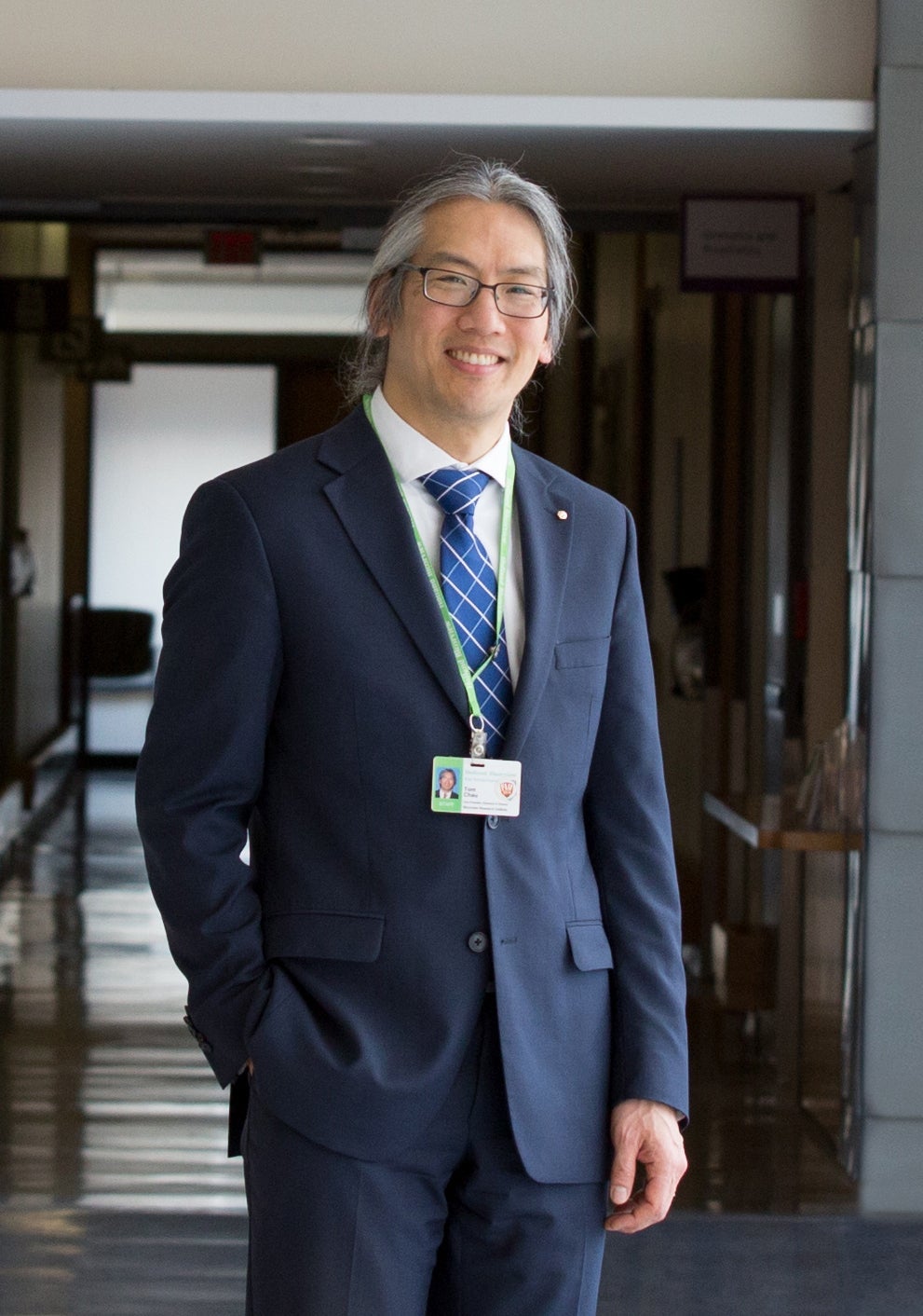 Dr. Tom Chau wearing a suit and standing with his hand in his pocket
