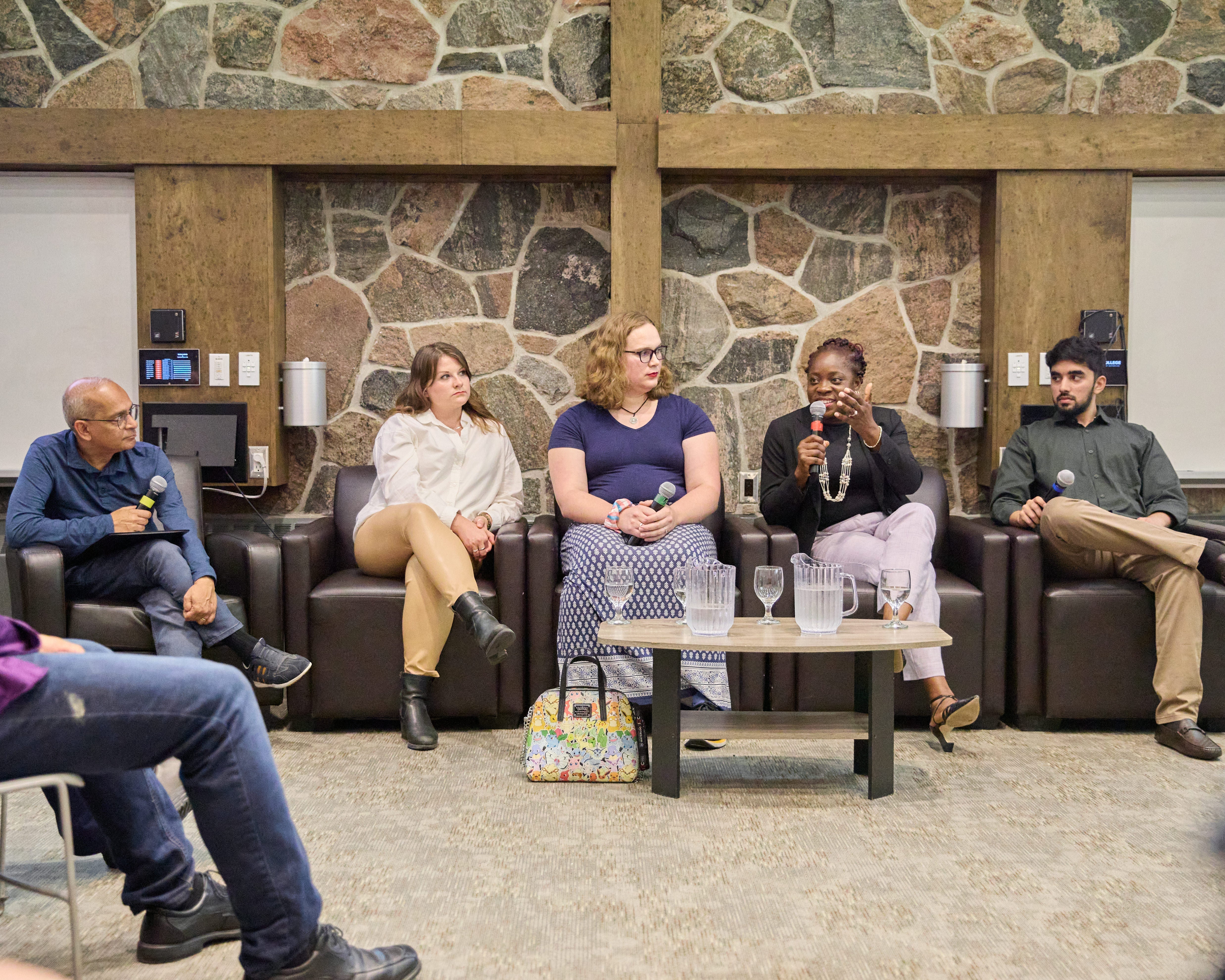 Panel of five people in conversation with an audience with microphones in their hands