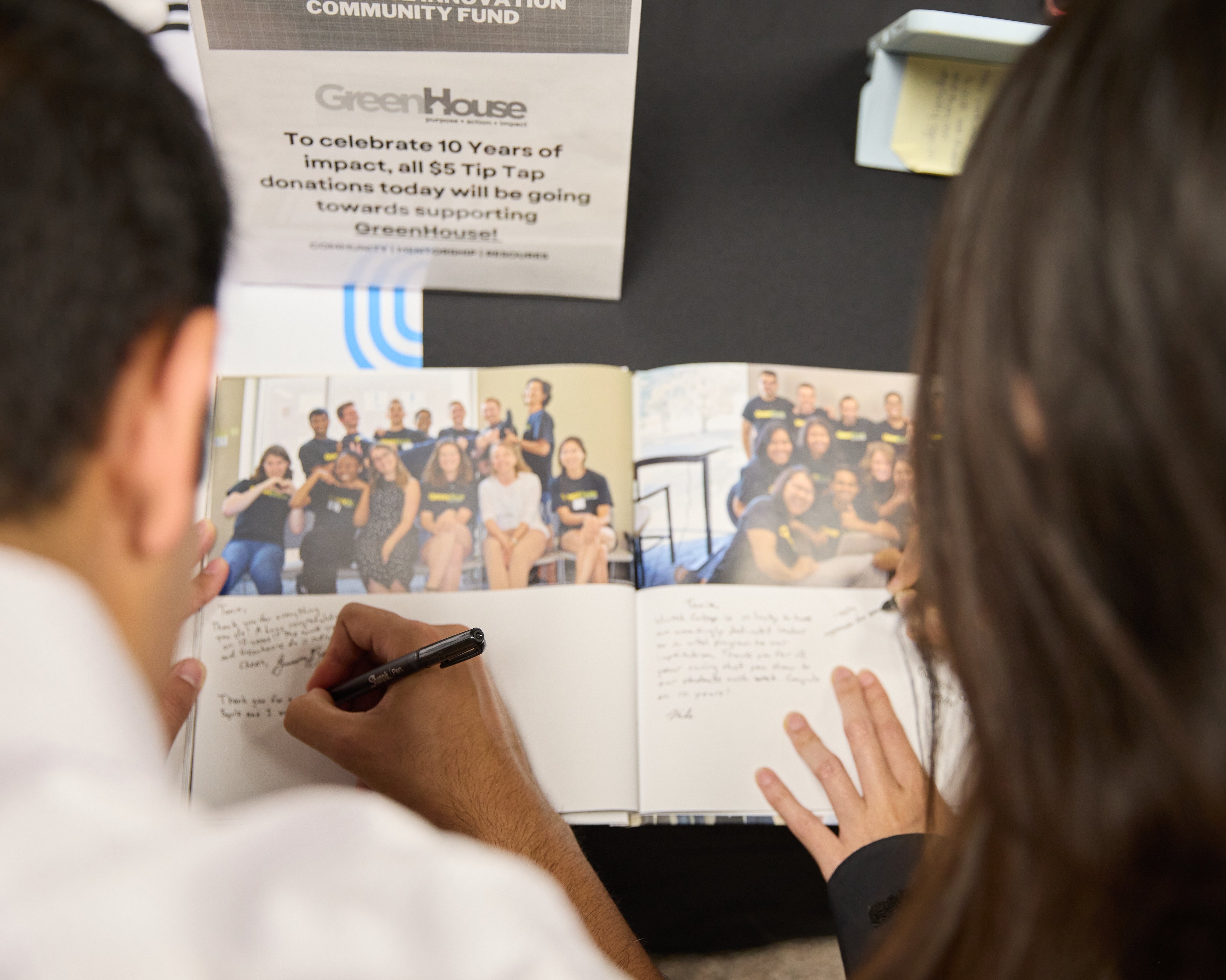 Two people signing their names into guest book