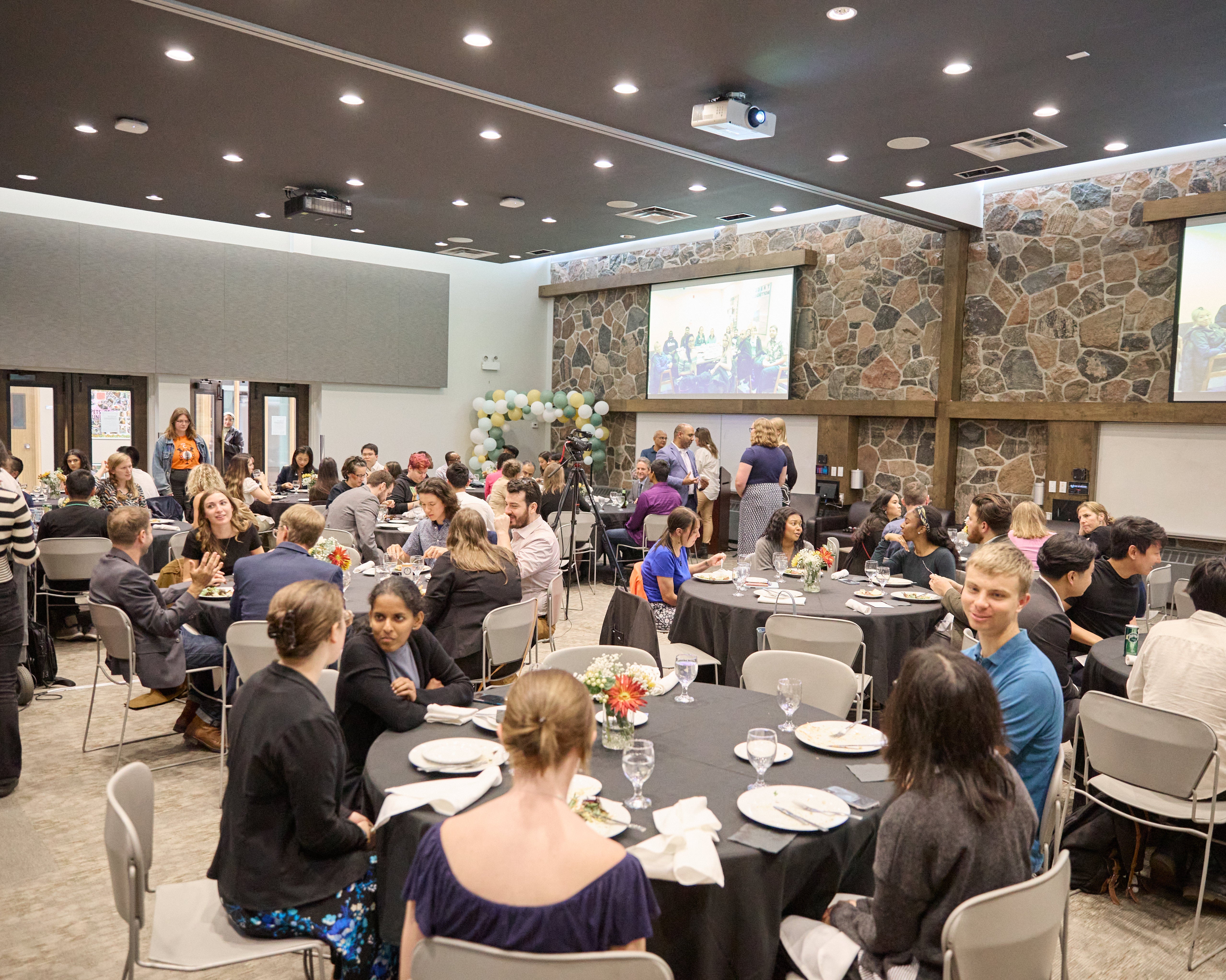 Large room with people seated around round tables