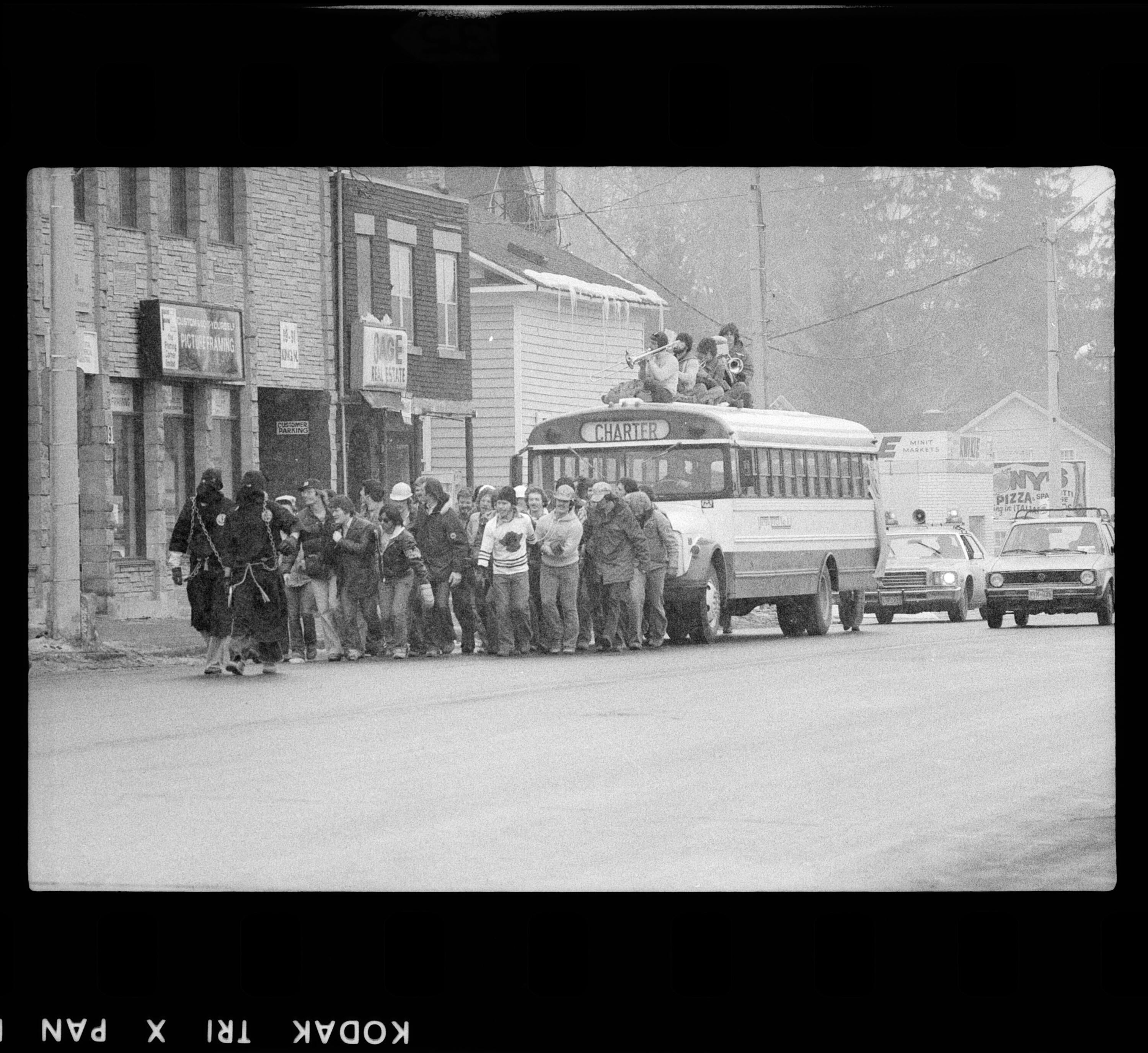 Black and white photo of students pulling a school bus