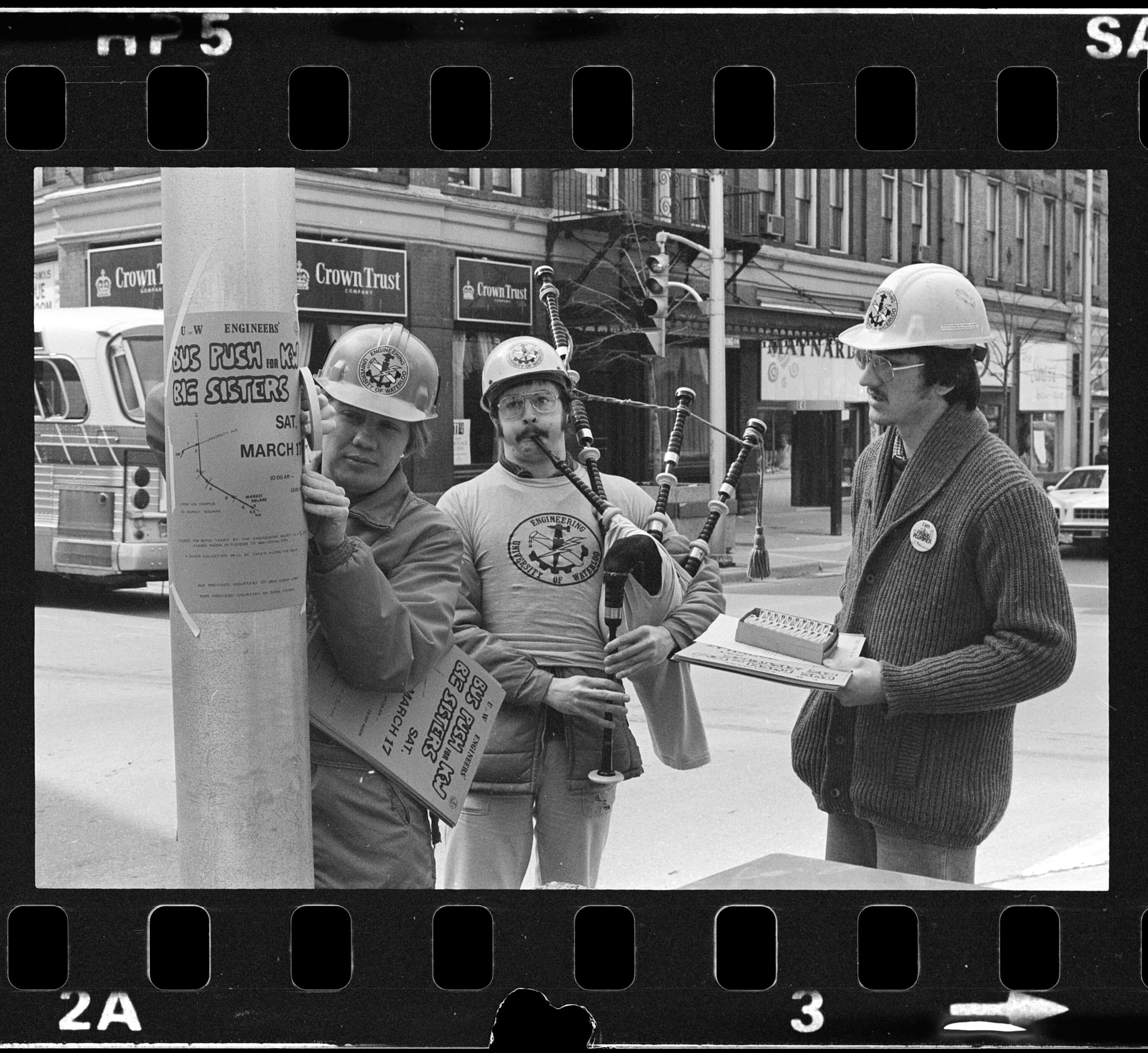 Black and white photo of people putting up signs
