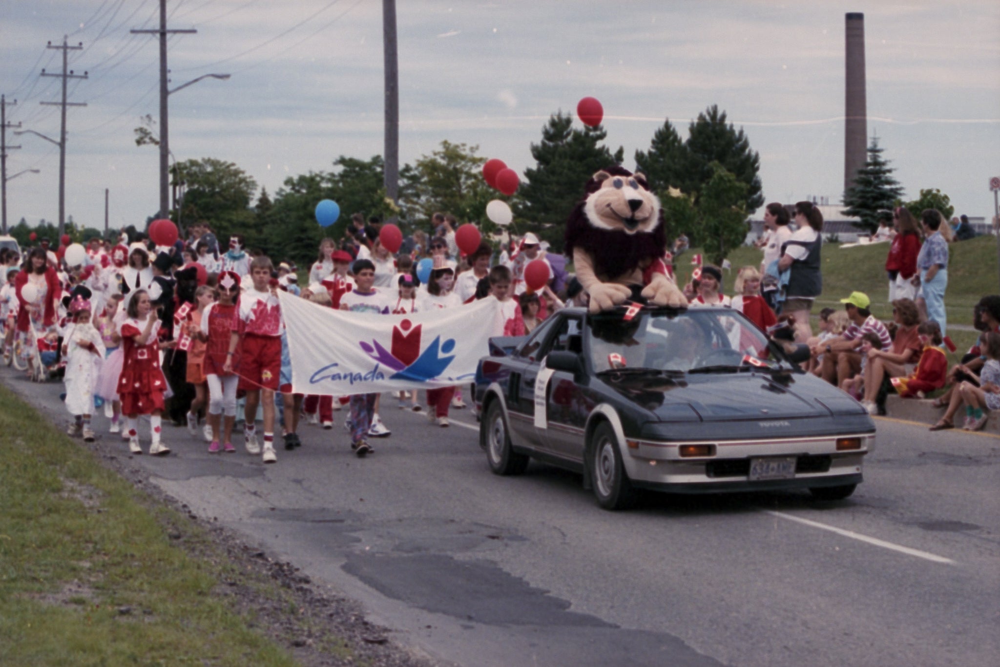 Pounce De Lion riding on a Toyota car with a crowd during a parade