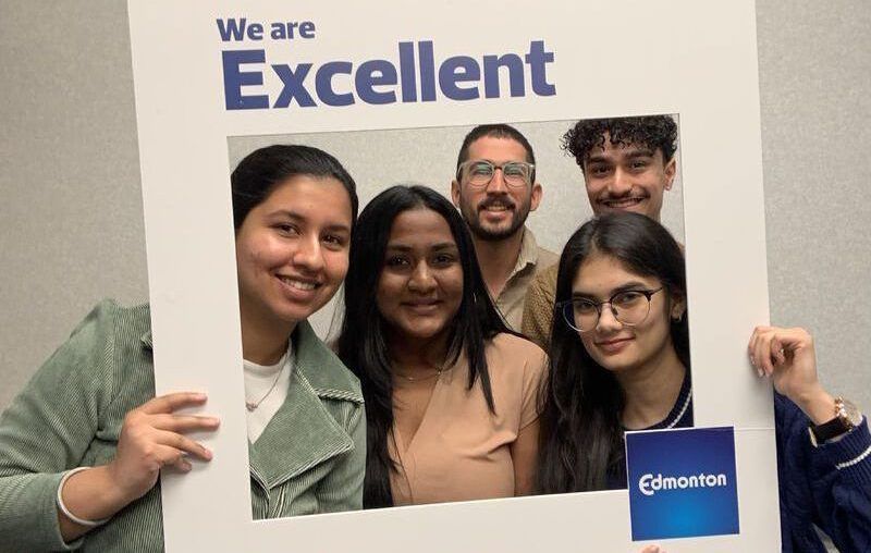 Preethi Raghuraman with interns from the University of Alberta at the City of Edmonton holding a "We are excellent" cutout