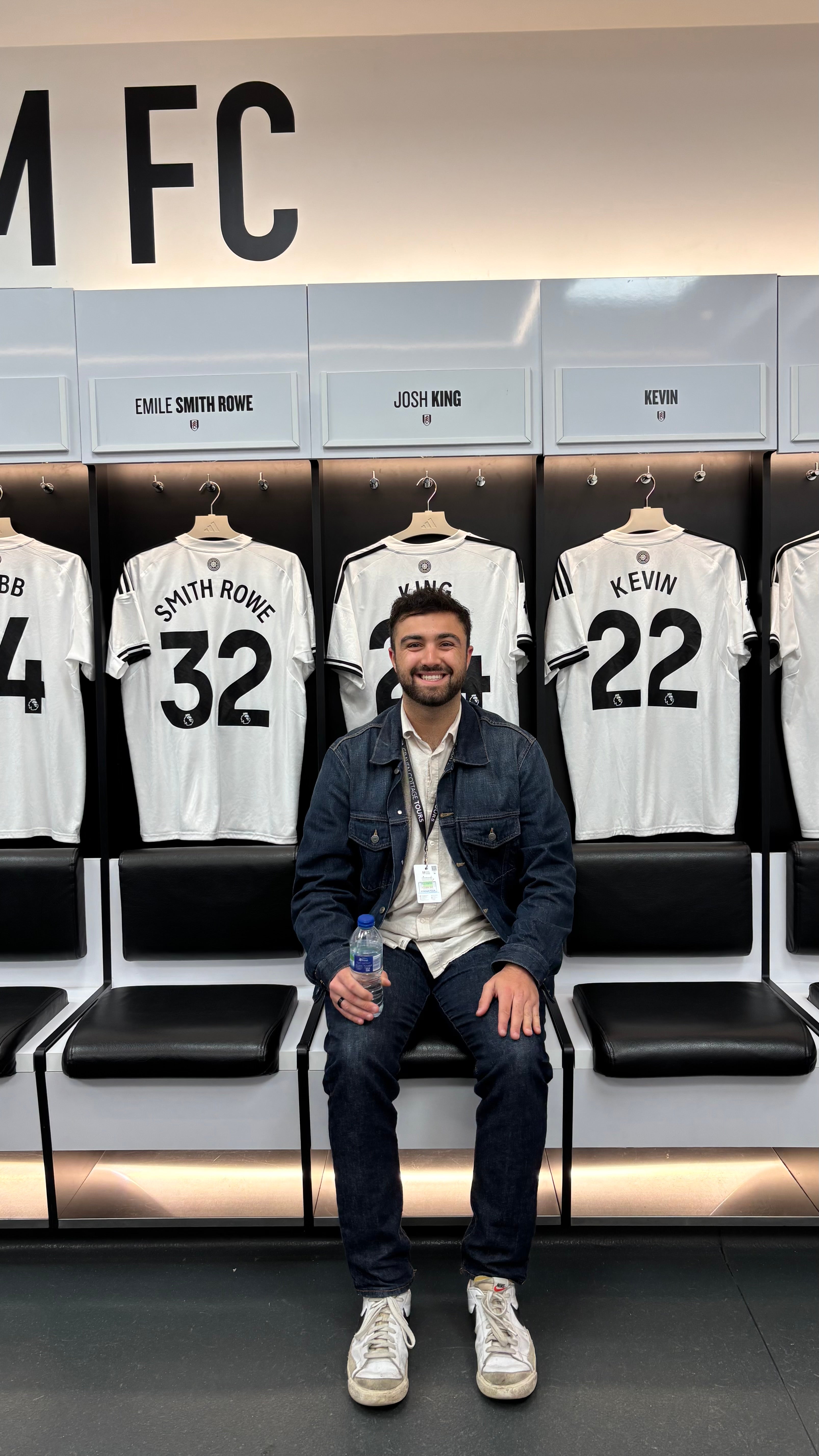 Ethan Rad sitting in a locker room with jerseys hanging on the wall behind him