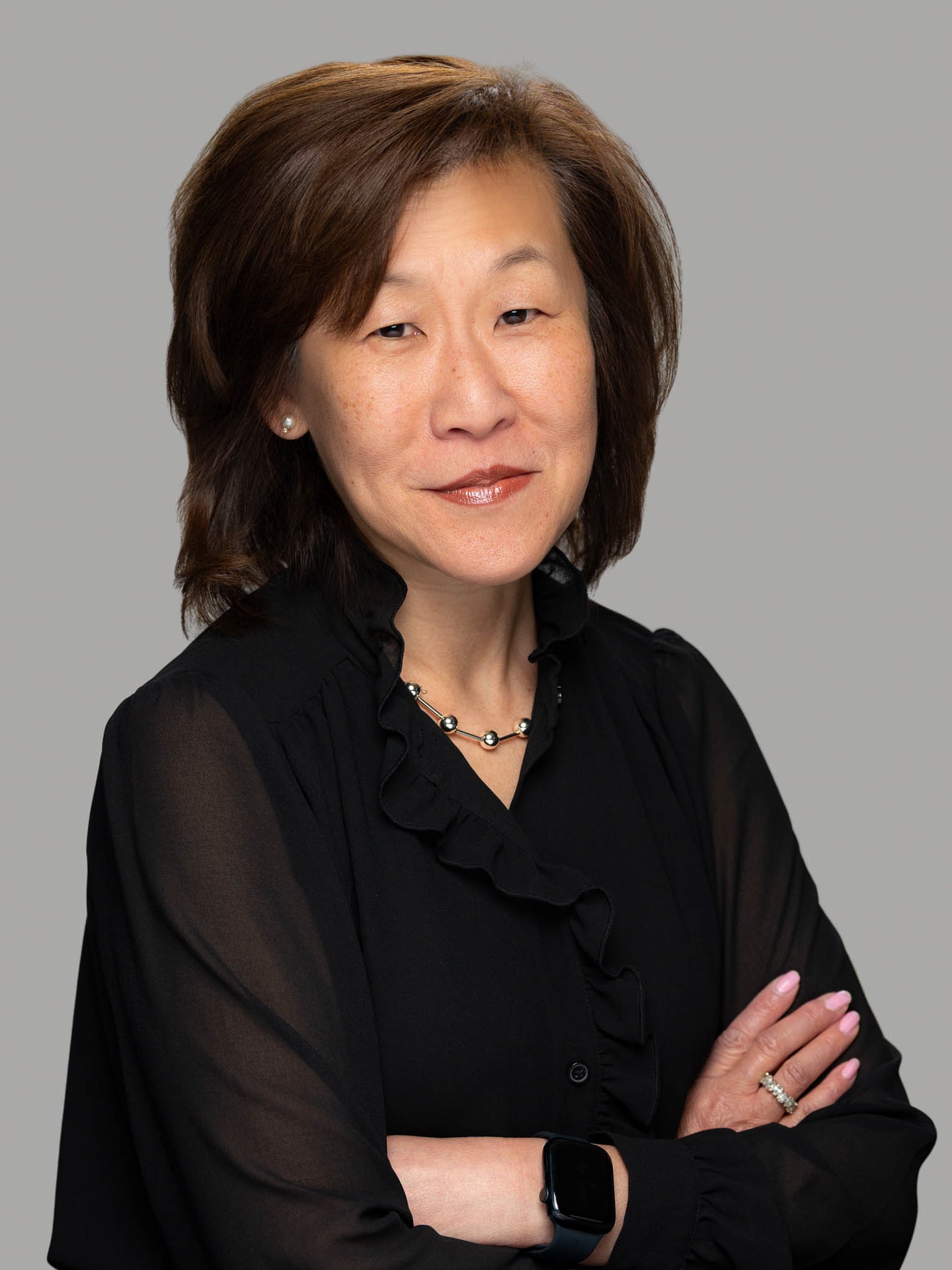 Jennifer Lee smiling and wearing a black-coloured long sleeve blouse with arms crossed