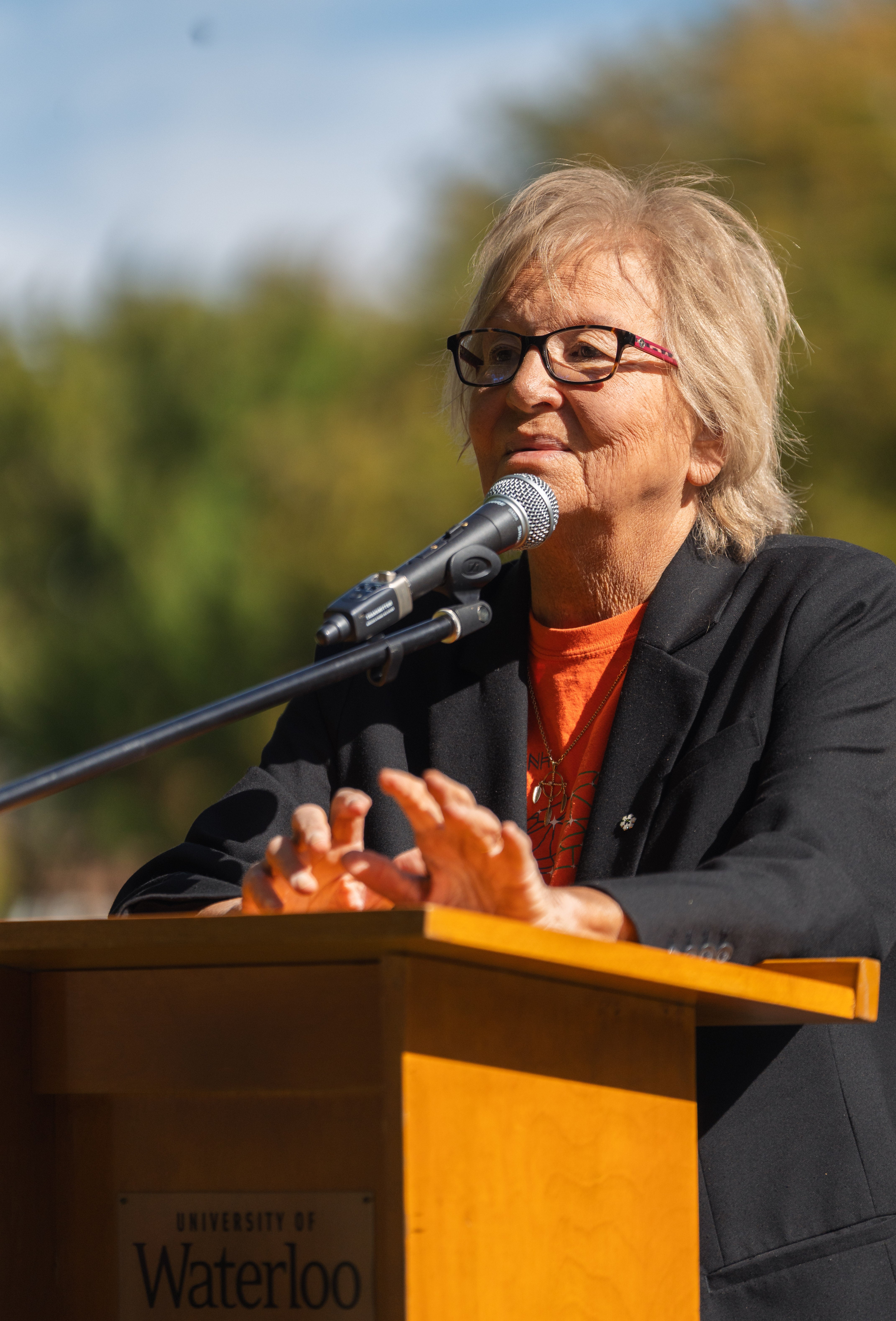 Carolyn King speaking at the podium in front of the Waterloo audience