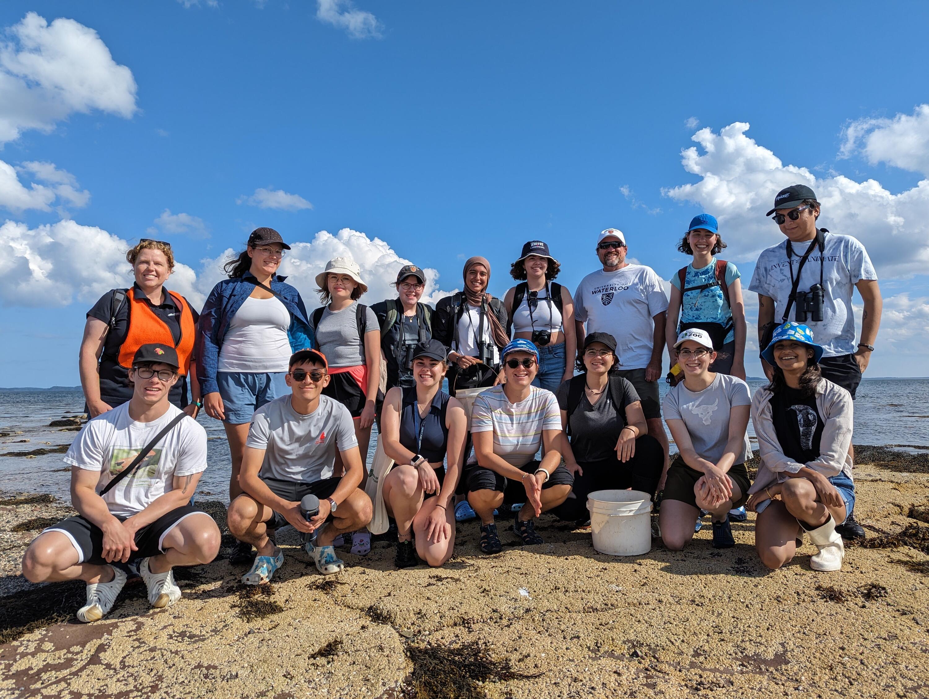 El-shayeb with classmates posing for a group photo on a beach.