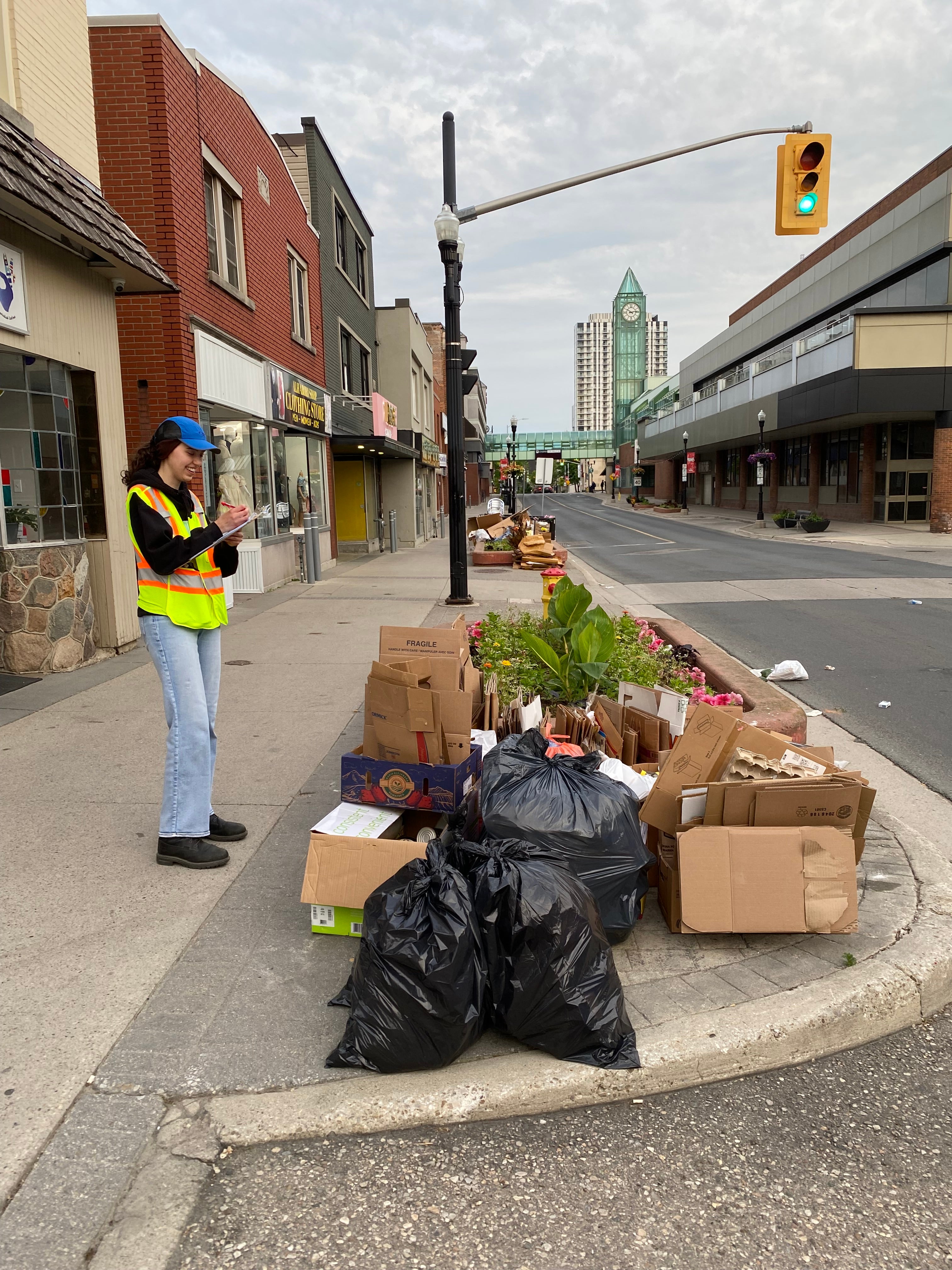 Chloe Sullivan in protective gear, writing down on a notepad about waste collection found on the side of street