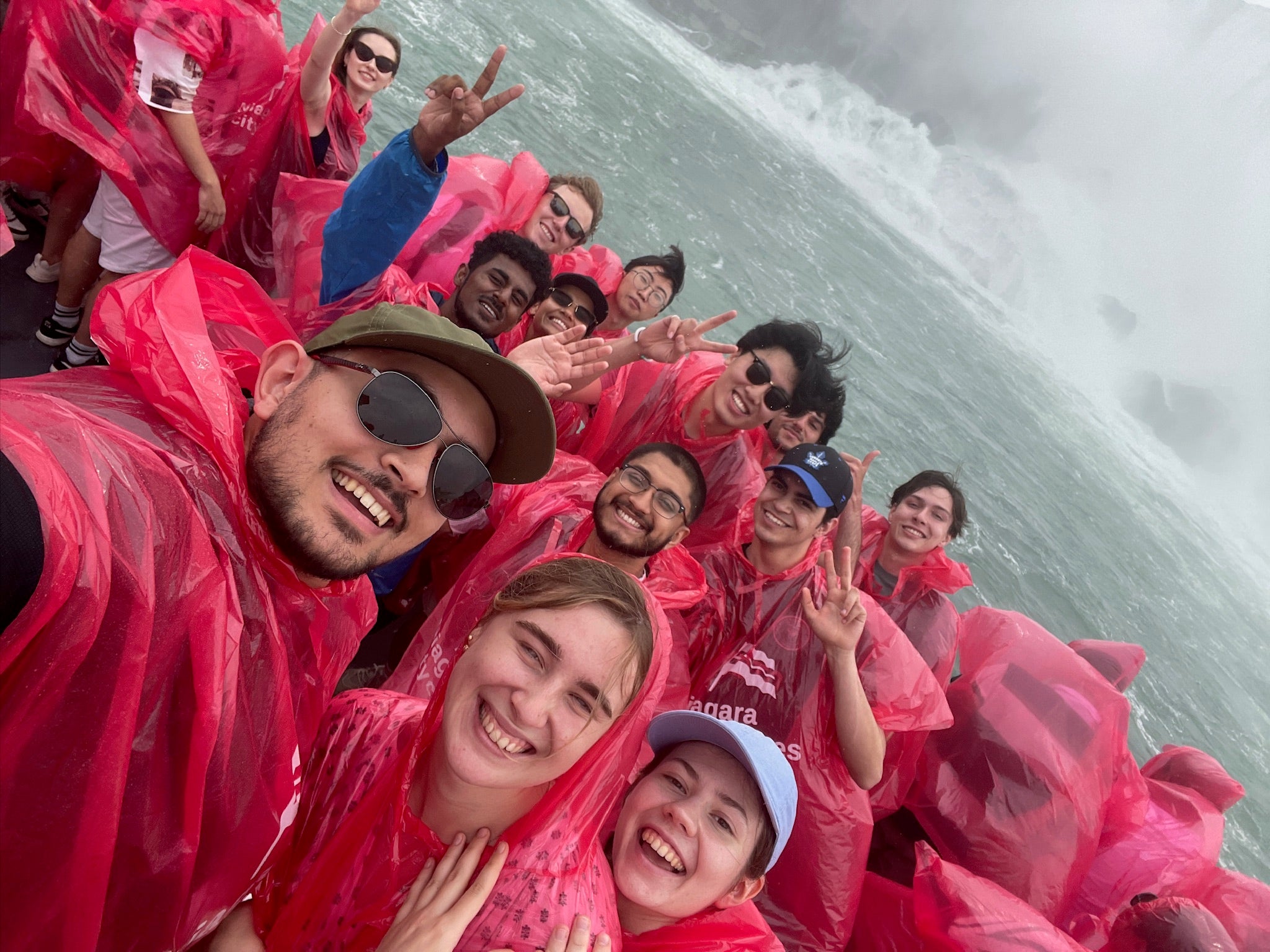 A group of young people in rain gear on a boat in Niagara Falls.