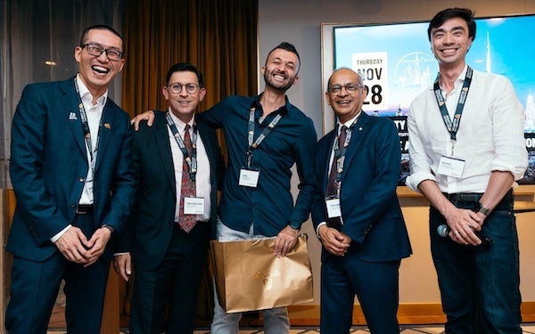 Five people laughing during a group photo at a reception