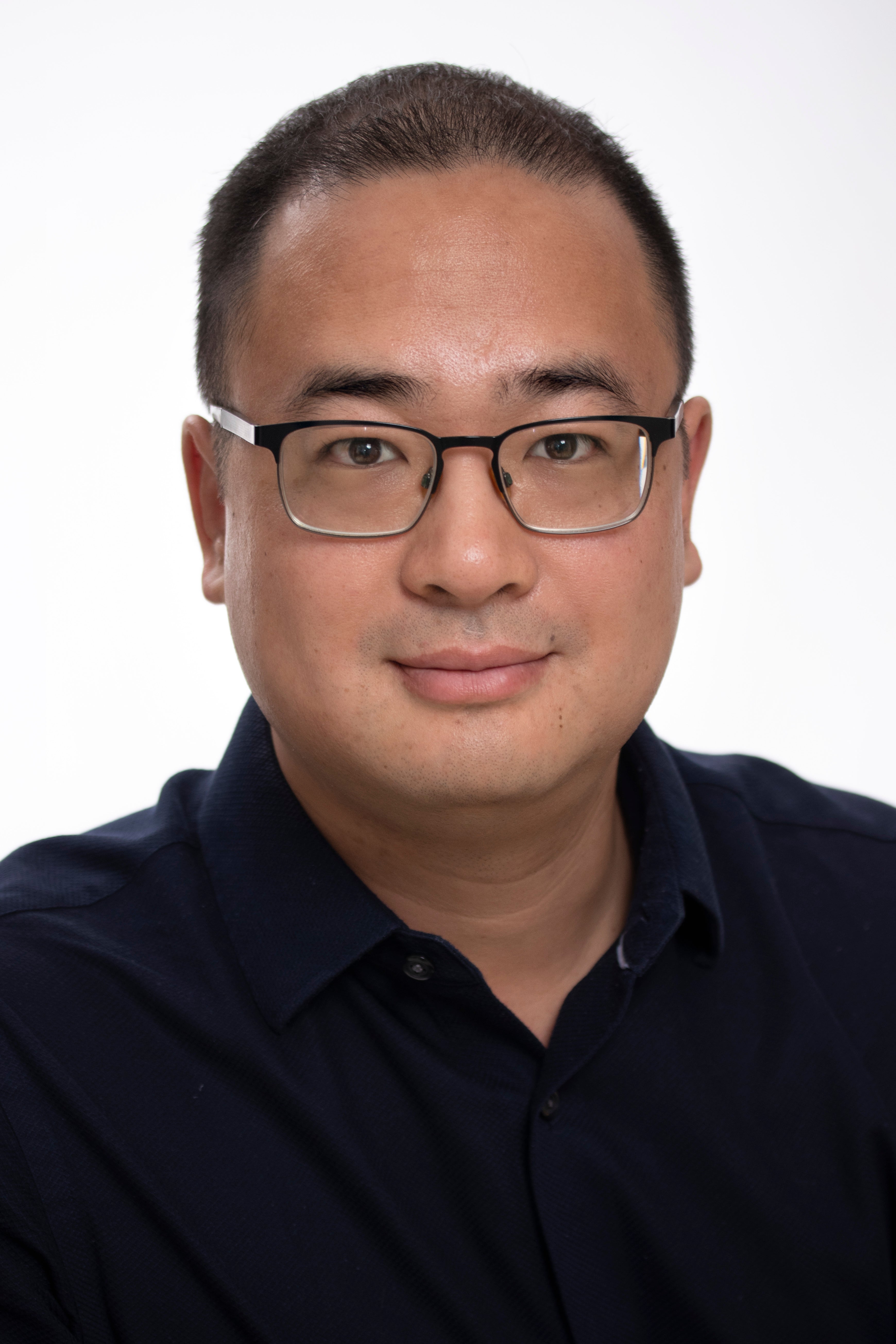 Wayne Lee wearing blue Polo t-shirt and dark framed glasses