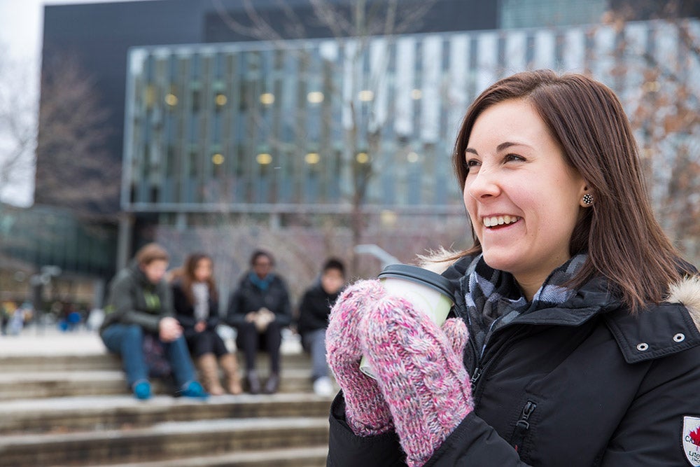 Female student warming her hands on a hot cup of coffee