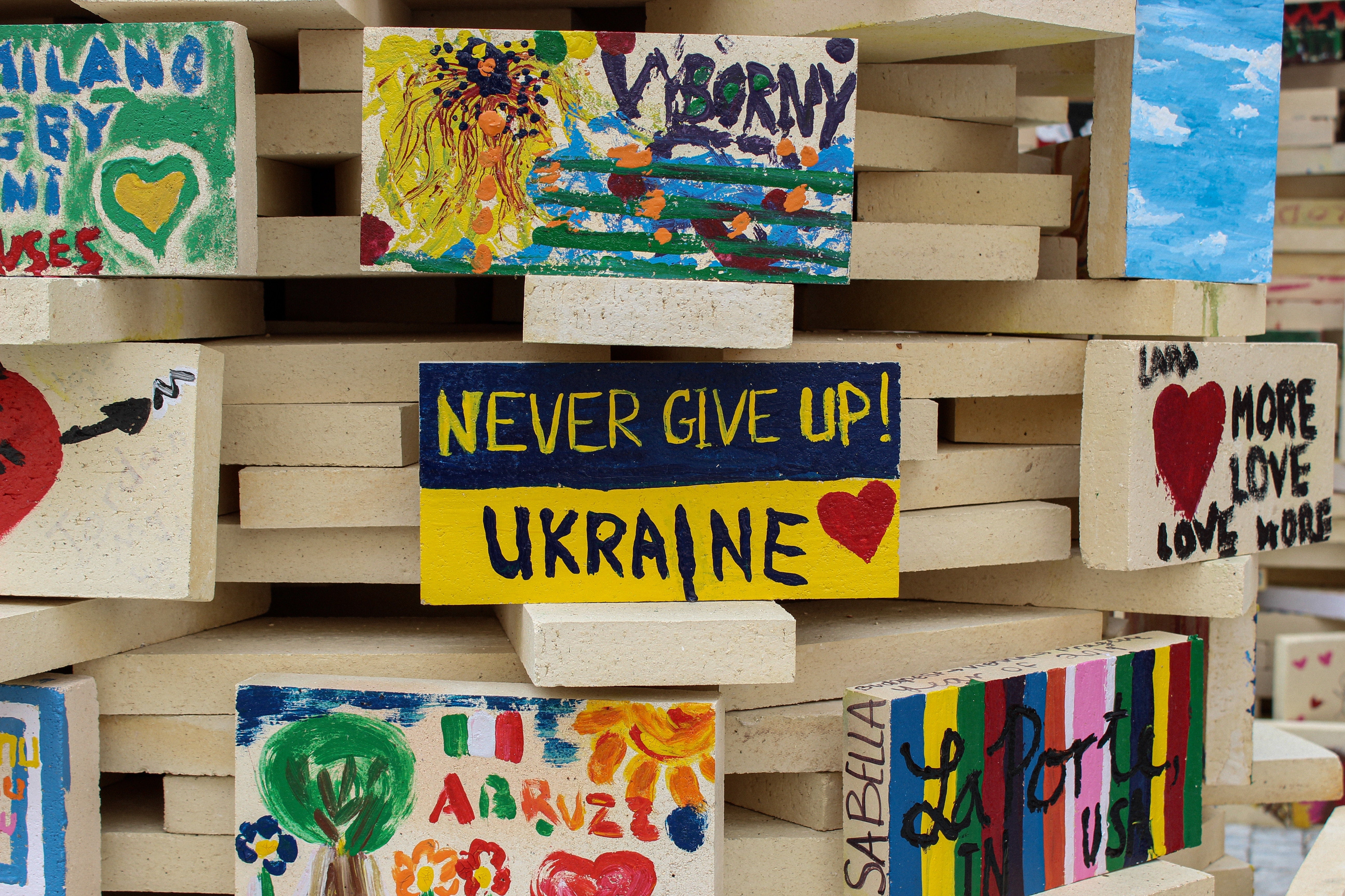 a wall with paintings and messages about Ukraine