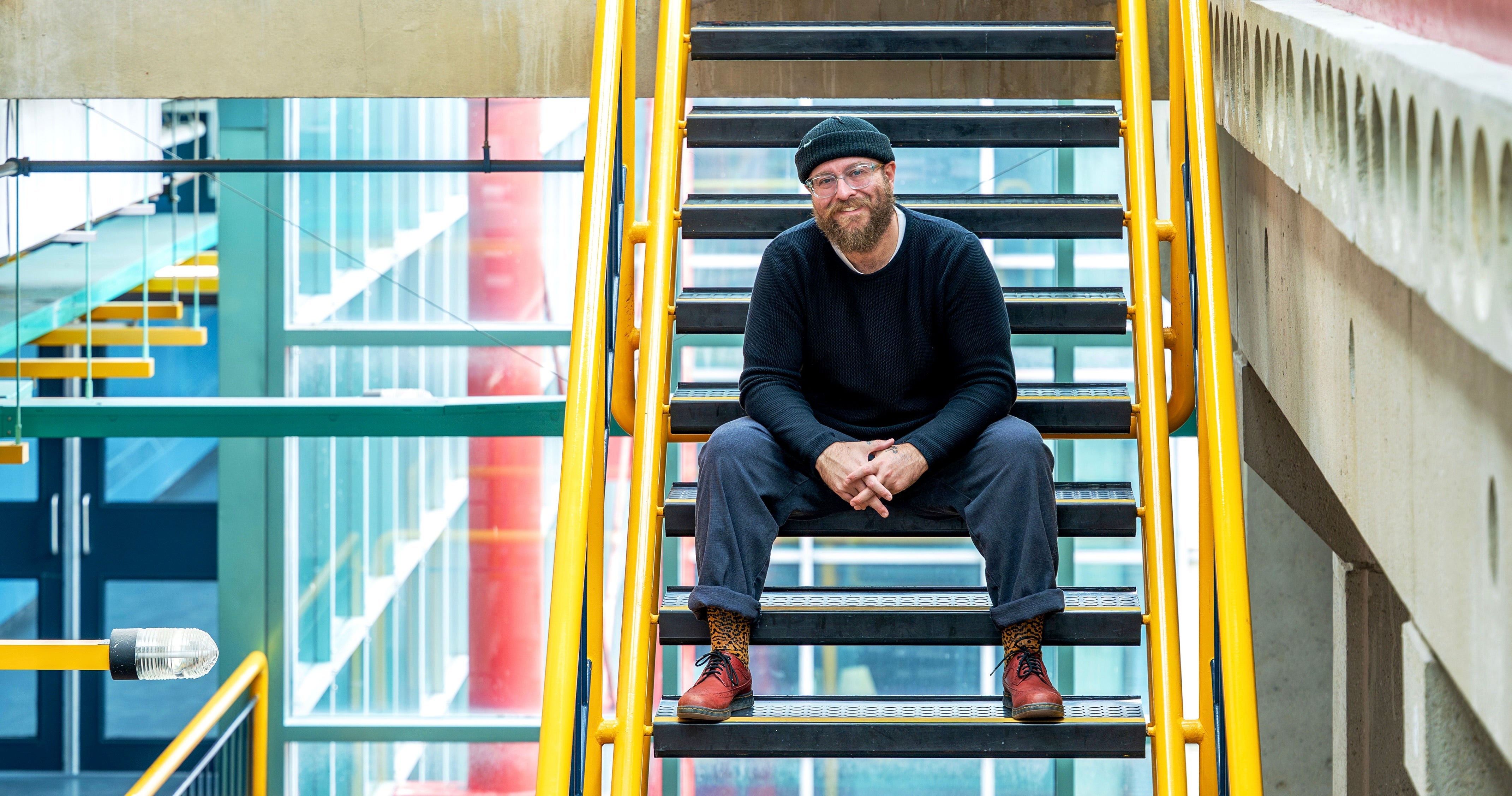 Zach Mckendrick sitting on stairs in open space