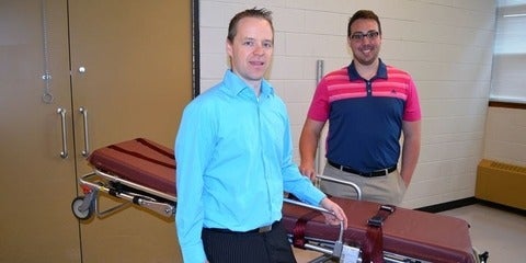 Steven Fischer and Daniel Armstrong standing beside a stretcher