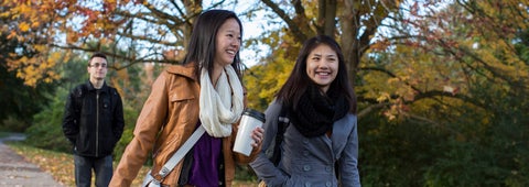 Three students walking on campus will fall foliage