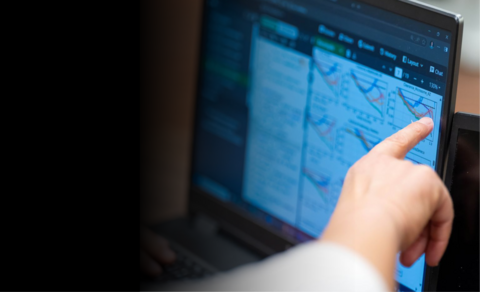 Hand point at data and graphs on a laptop