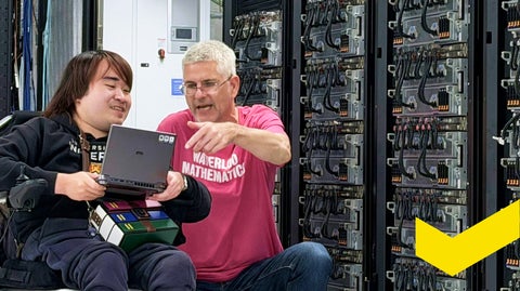 Two people looking at a laptop in a data centre