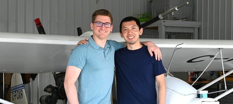Jeremy Wang standing with Ribbit co-founder in front of a small plane within an airplane hanger