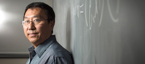 Ming Li standing in front of a blackboard 