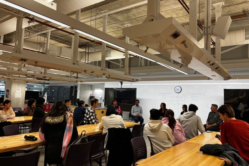 Image of the panel event organized, students sitting at tables listening to the panel