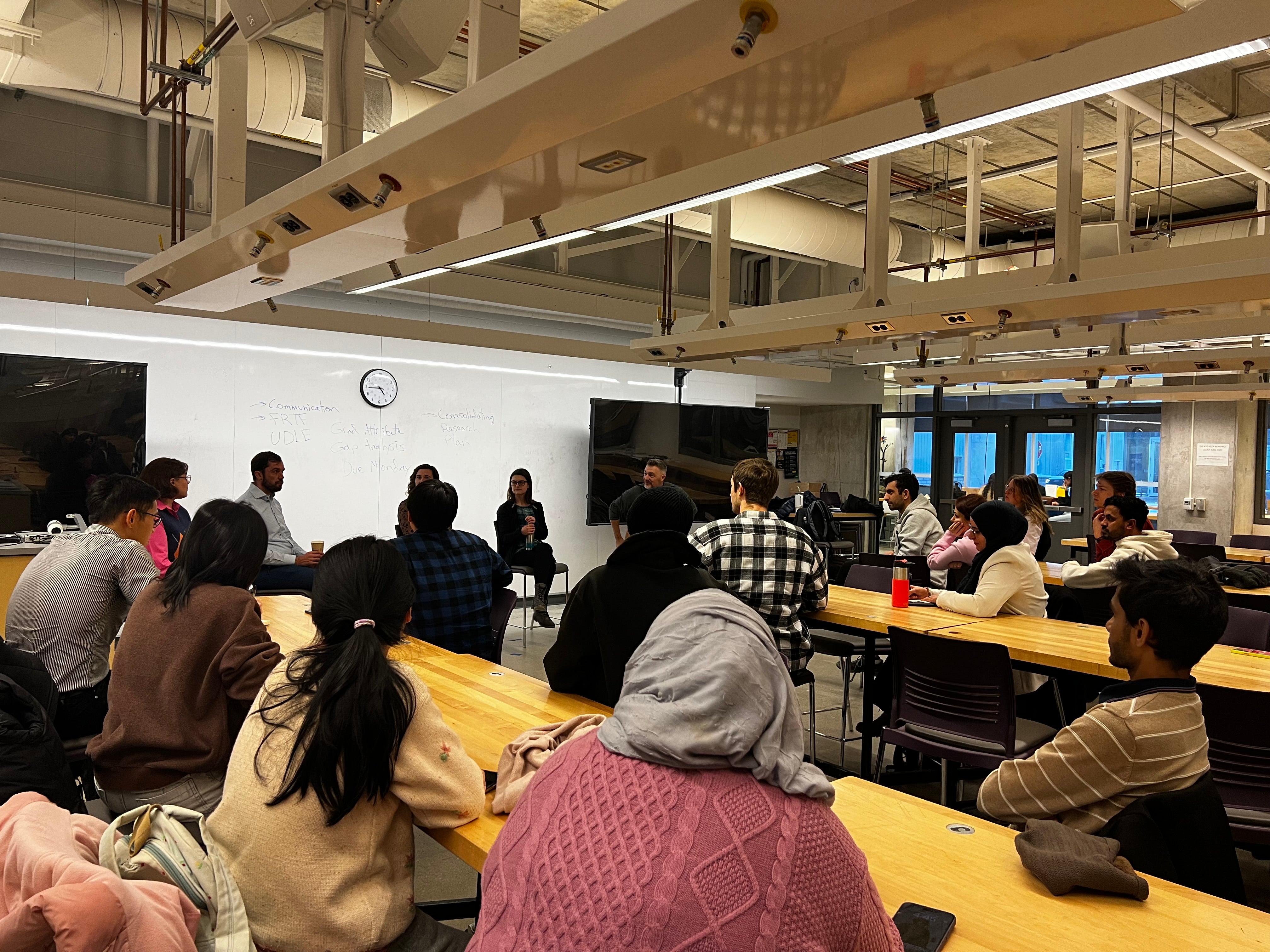 Image of the panel event organized, students sitting at tables listening to the panel