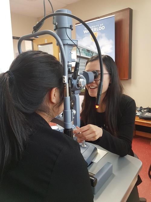 A female student examines a woman’s eyes using a slit lamp