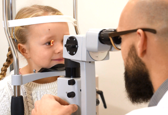 Child looks through a slit lamp during an eye test