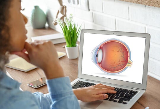 Young woman looks at laptop screen displaying an eye diagram