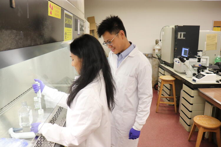 Dr. Will Ngo assists a graduate student with a test in his lab