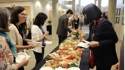 Conference attendees select food from a lunch table.