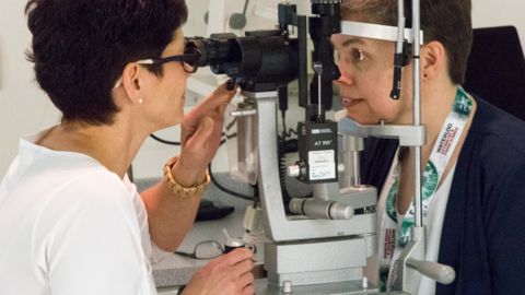 Optometry alumna examining another woman using a slit lamp