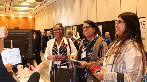 three women talking to vendor in conference