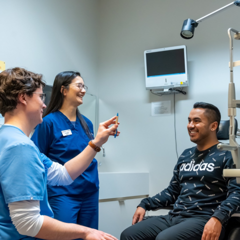 A student tests a patient's vision with an instructor overseeing the exam.
