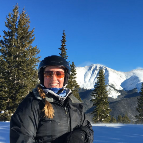 Kristine Dalton stands in the snow in front of a mountain scene in Europe