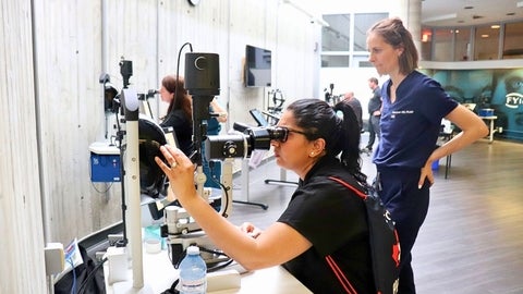 Dr. Sarah MacIver looks on as a student practices on laser equipment