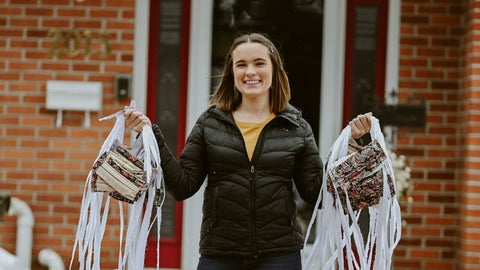 Olivia holds up bunches of face masks at the entrance to her home
