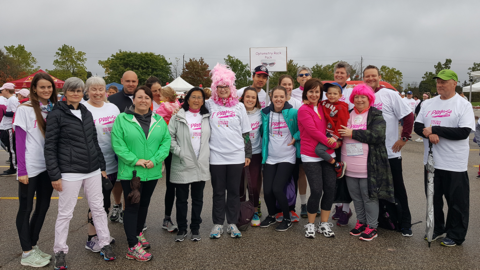 A group of smiling people wearing running gear stand in a parking lot under a cloudy sky