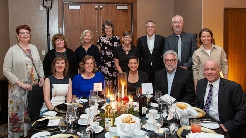 Alumni gather around a table at a past reunion.