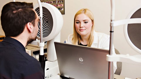 A student examines a patient with a corneal topographer