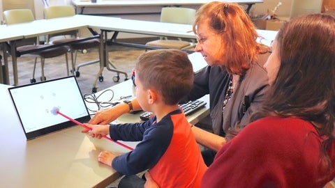 Dr. Susan Leat assists a young patient with a new eye exam approach