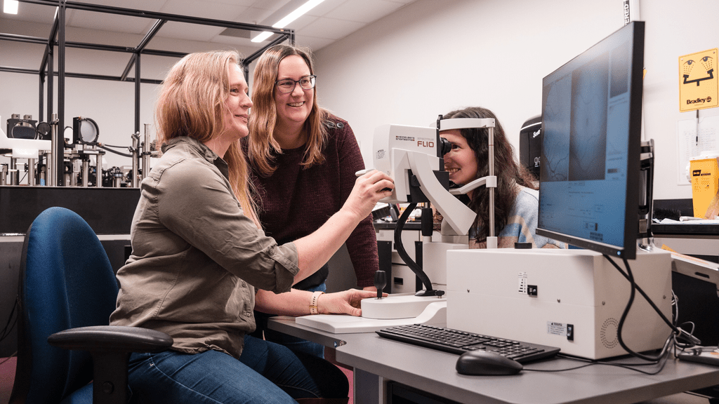 Dr. Jennifer Hunter works in her lab with a participant looking into a slit lamp